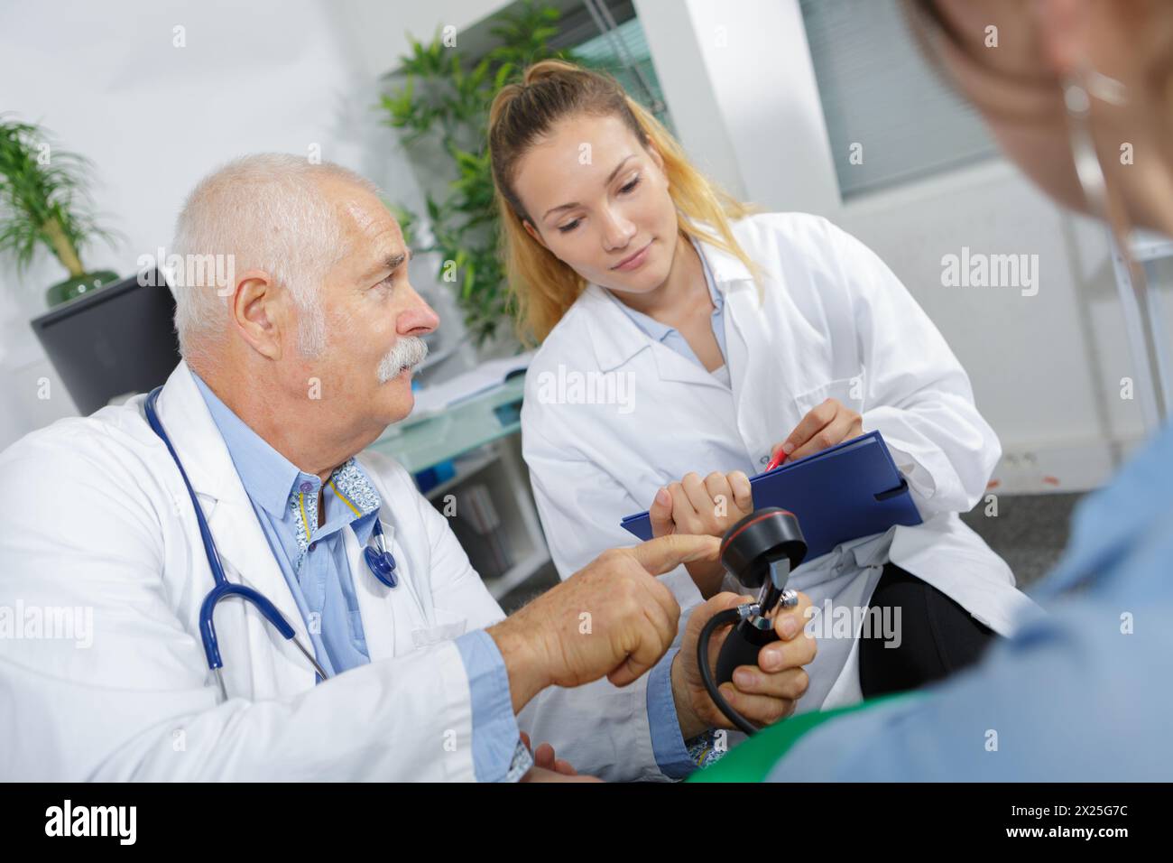doctor training nurse to read blood pressure gauge Stock Photo
