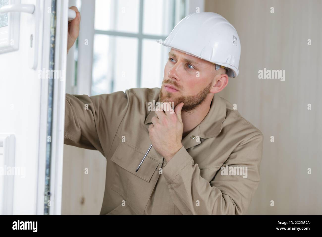 young handsome builder thinking about something while holding clipboard Stock Photo