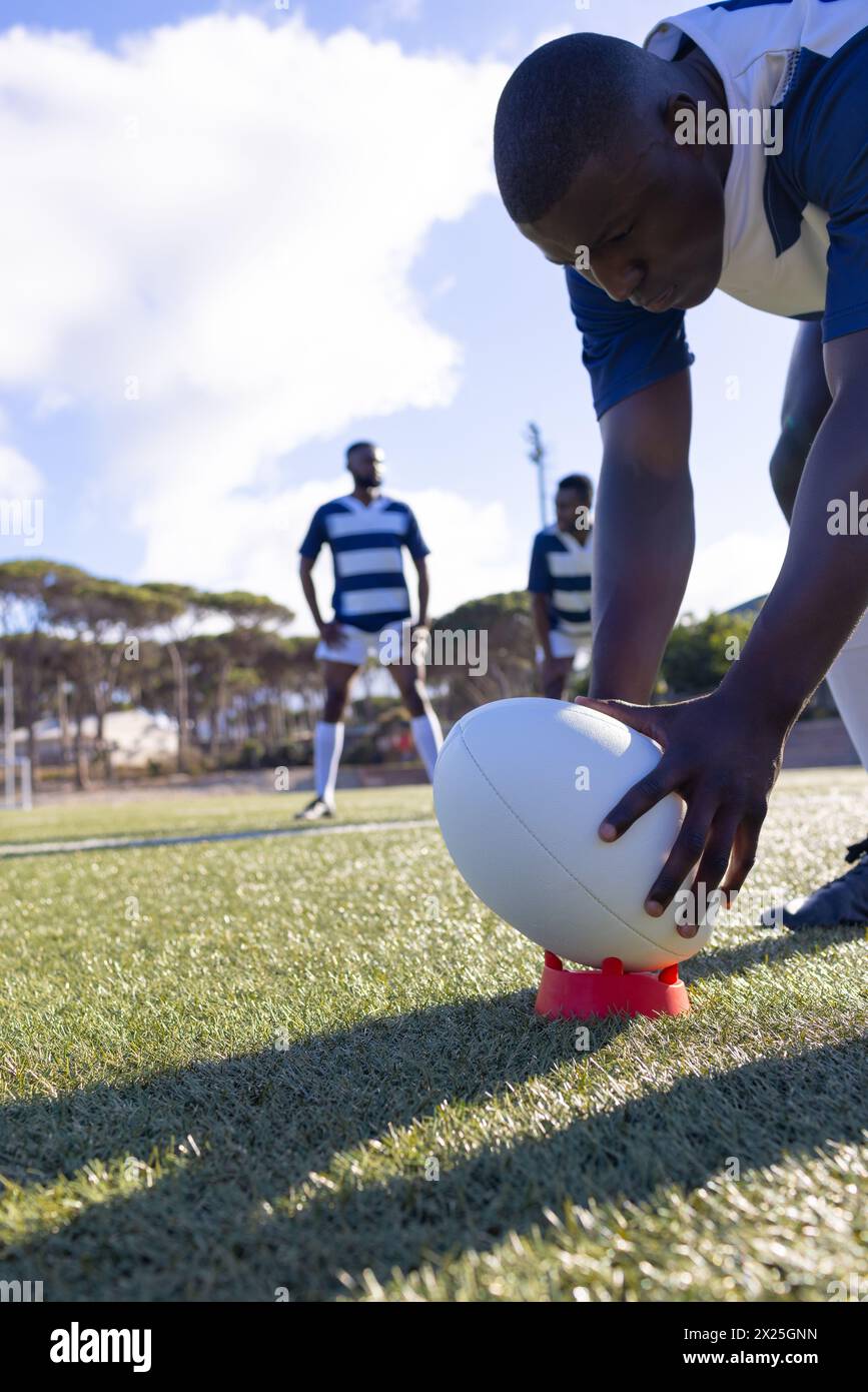 Three young African American male athletes ready for rugby, one setting the ball Stock Photo