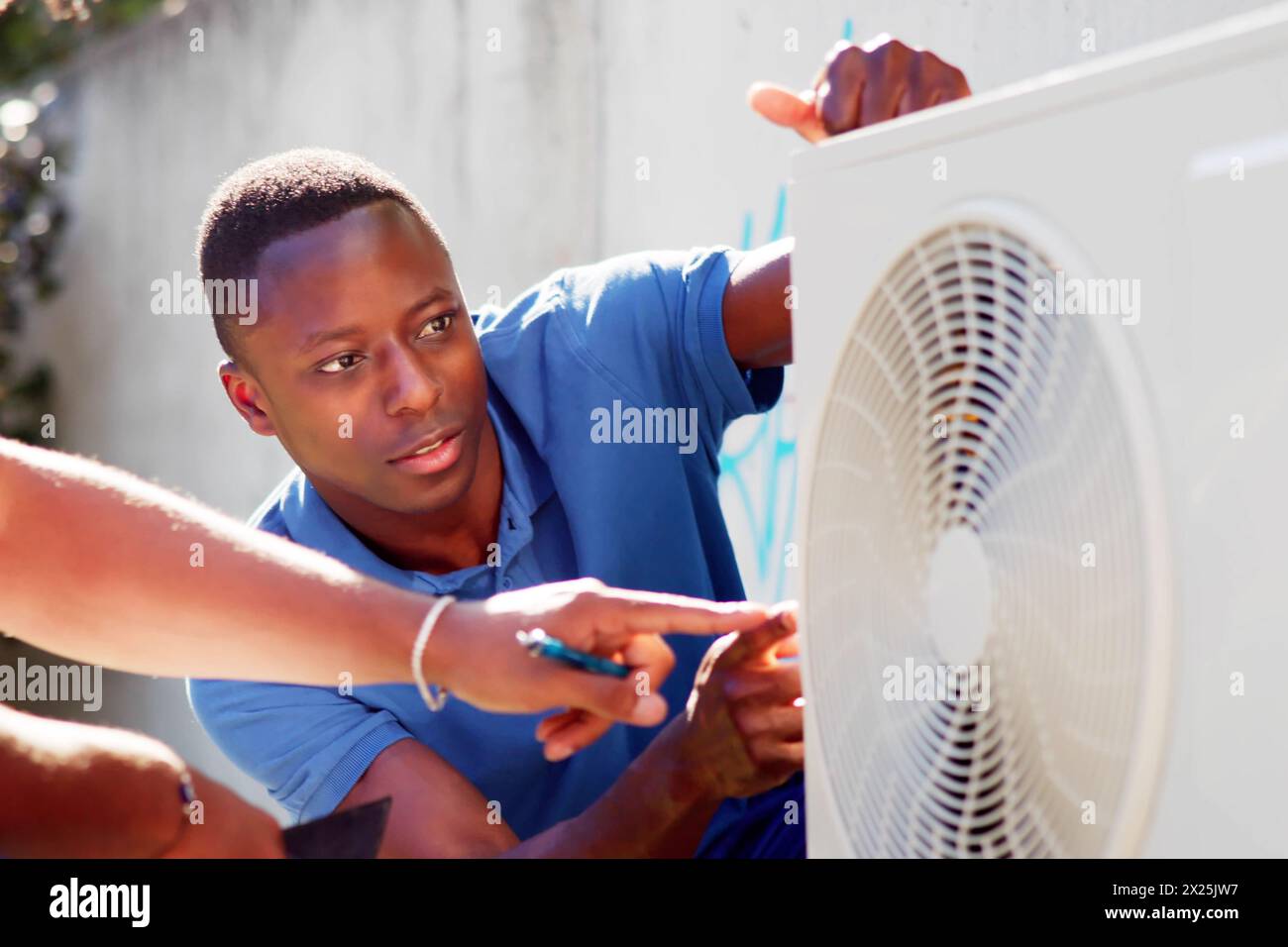 HVAC technician installing air conditioner for optimal comfort Stock Photo