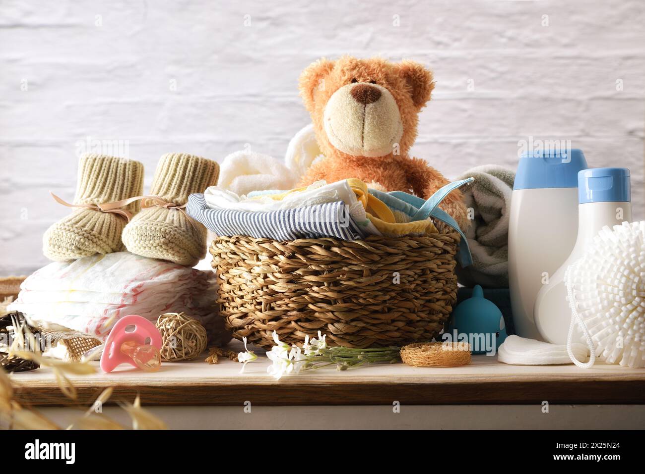 Clothes and accessories for clothing and baby grooming on wooden chest of drawers in room with white brick wall. Front view. Stock Photo