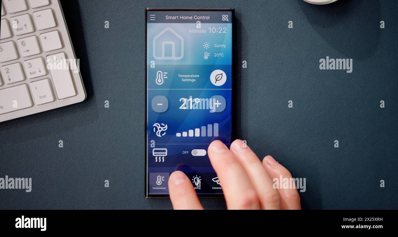 Hand Using Mobile Phone With Home Control System On Screen Stock Photo