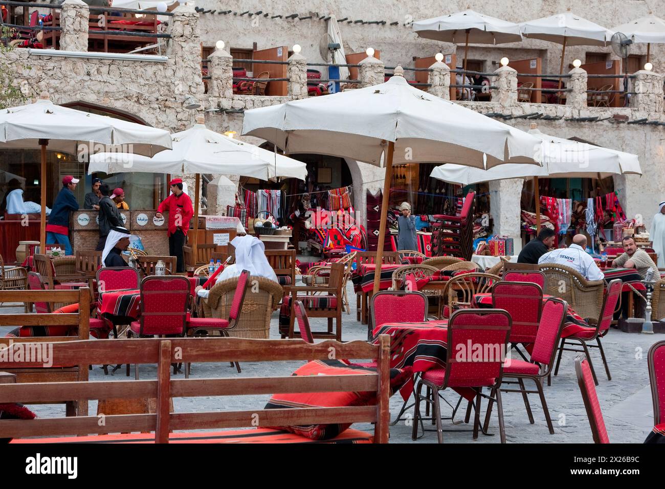 Doha, Qatar.  An outdoor coffee shop near the traditional market.  Arab men smoking water pipes (hookah, nargileh, sheesha). Stock Photo