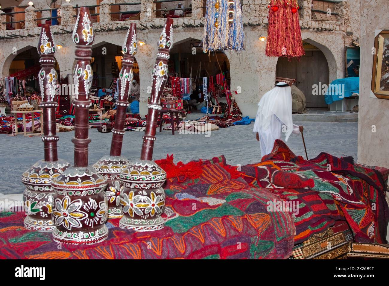 Doha, Qatar.  Market Scene, in the Recently Modernized 'Traditional' Market. Decorated coffee grinders on the left.   Qatari Man in Dishdasha with Whi Stock Photo