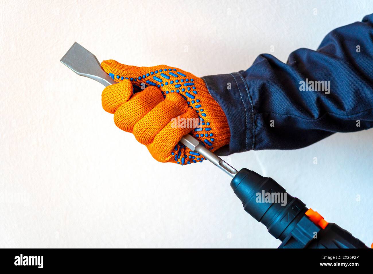 close-up. hands in protective gloves, hammer drill, installation of a chisel in a perforator. The concept of replacing the rotary drill. Stock Photo