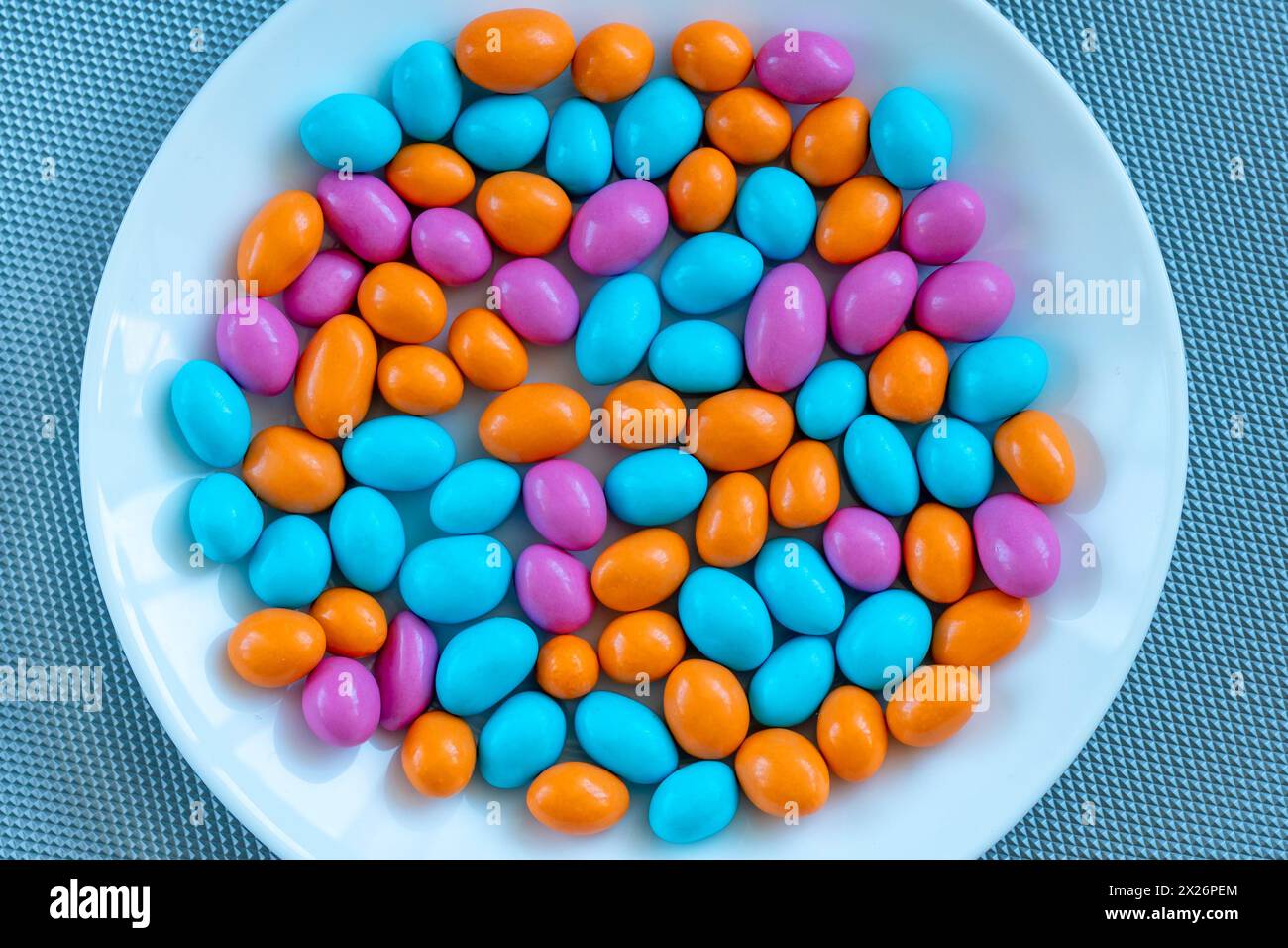 texture with multi-colored stones on a white plate. objects of different colors on a  background. multicolored pebbles Stock Photo