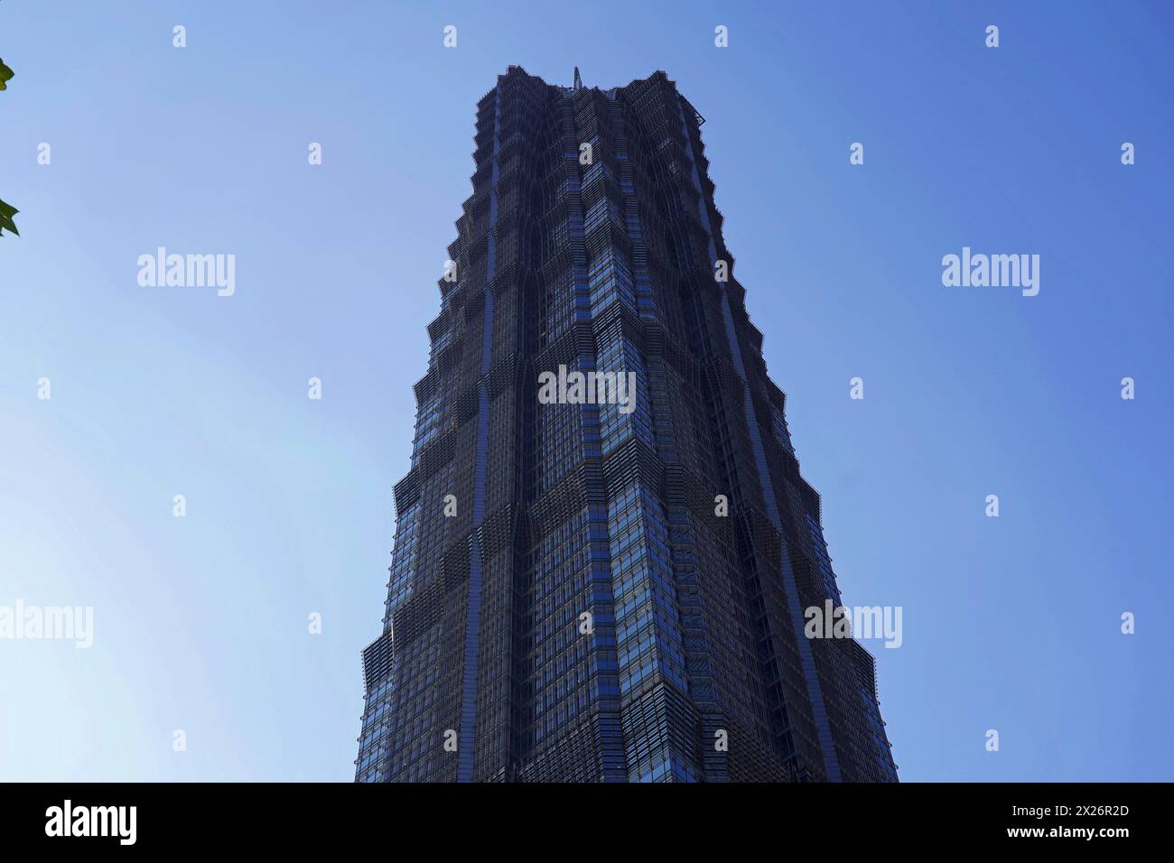 The facade of a geometrically designed skyscraper stands out against the blue sky, Shanghai, China Stock Photo