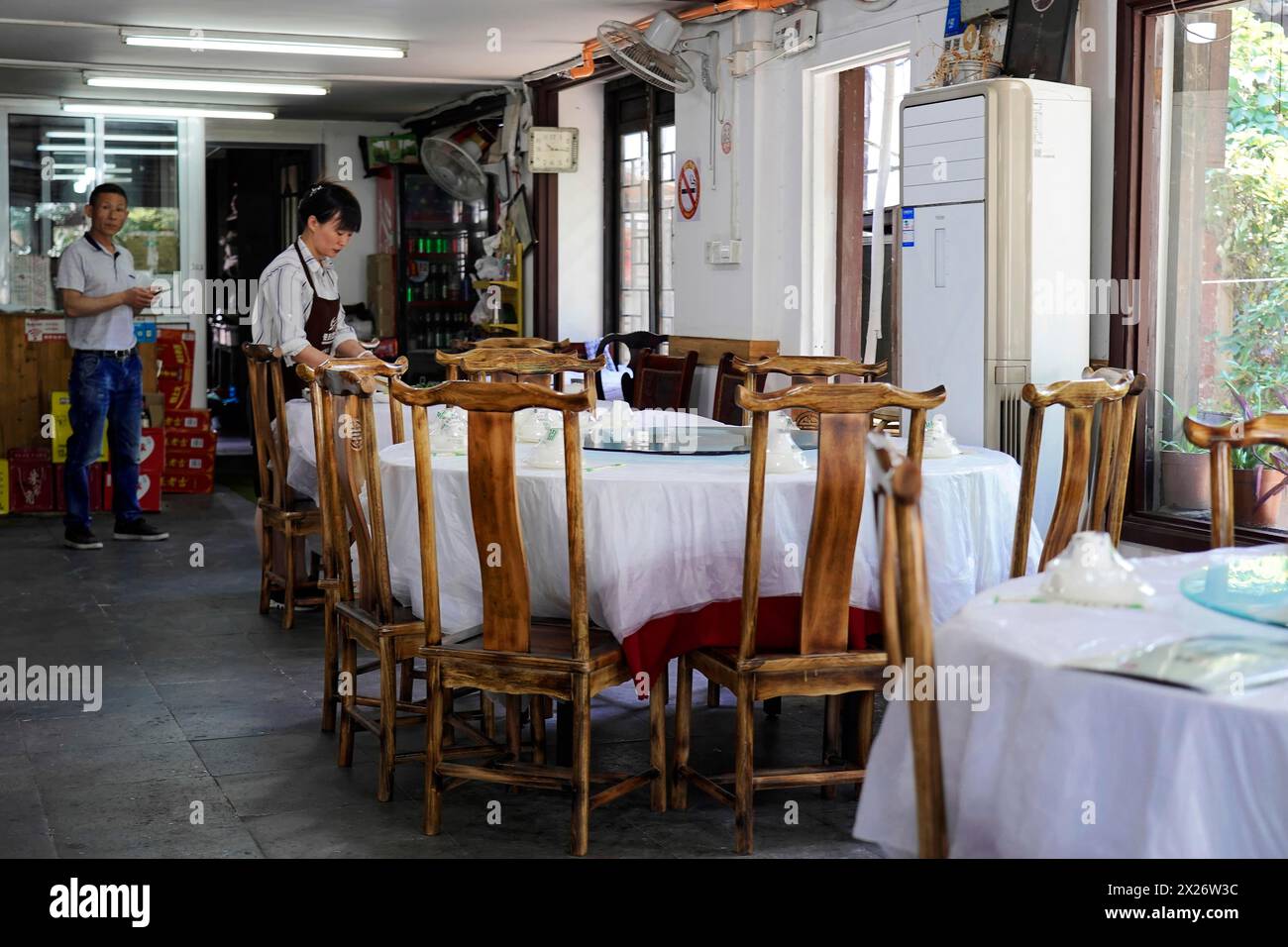 Excursion to Zhujiajiao Water Village, Shanghai, China, Asia, Empty restaurant with wooden tables and chairs and a visible employee Stock Photo