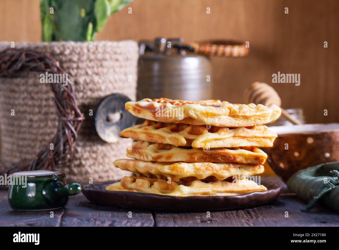 Belgian waffles served with honey, cream and sai on a wooden background. Rustic style, selective focus. Stock Photo