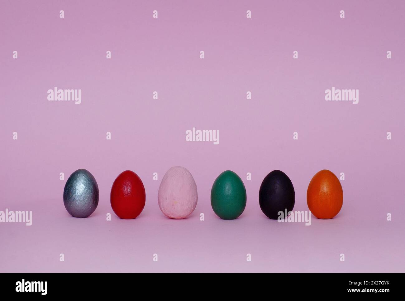 Six assorted ornamental hand painted eggs stand on paper background. Easter composition. Stock Photo