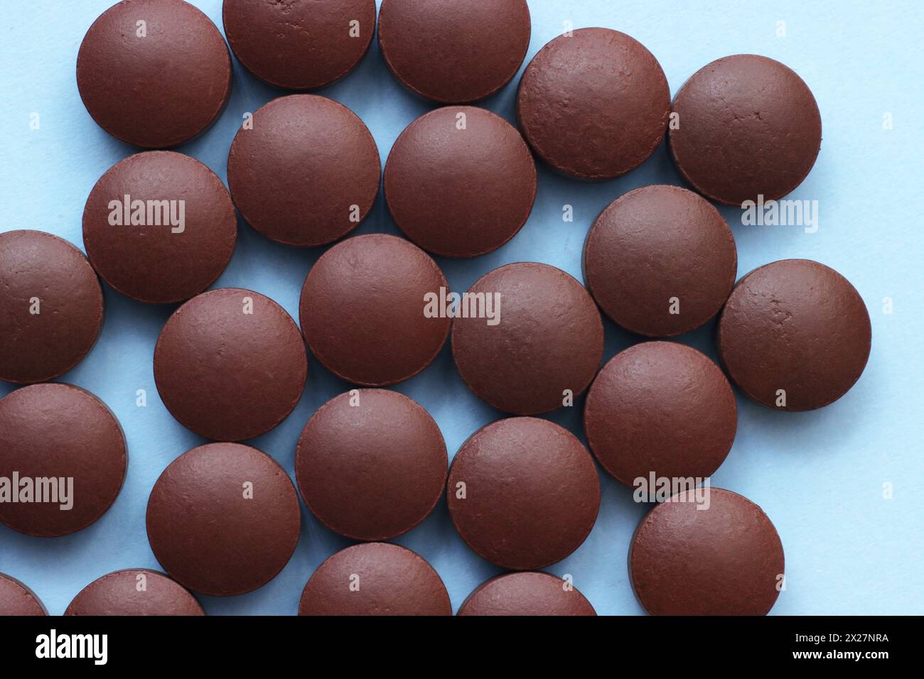 Red dietary supplement pills on a blue background. A bunch of medical pills. Stock Photo