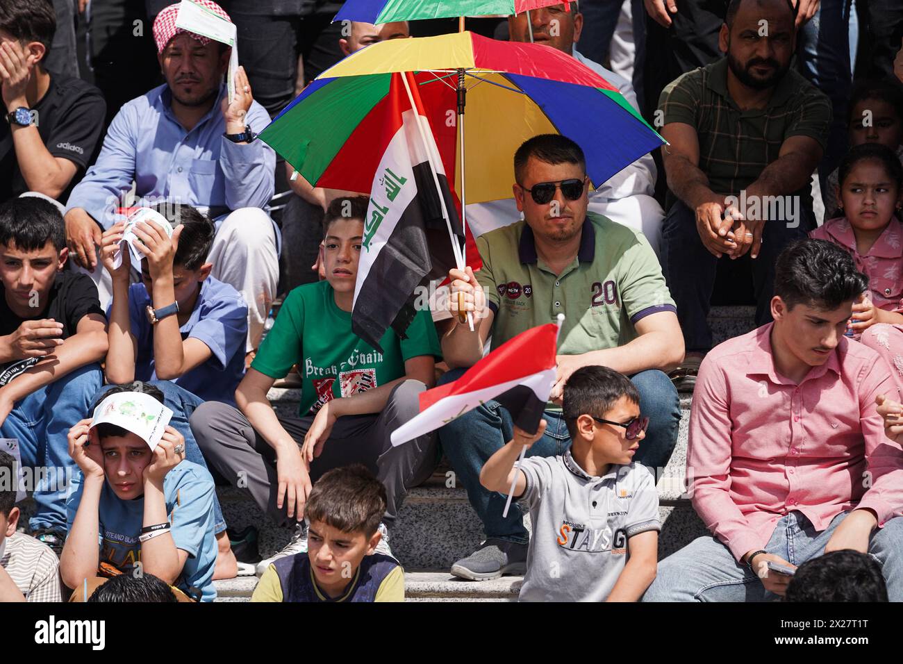 Mosul, Iraq. 20th Apr, 2024. Iraqis cover themselves with umbrella