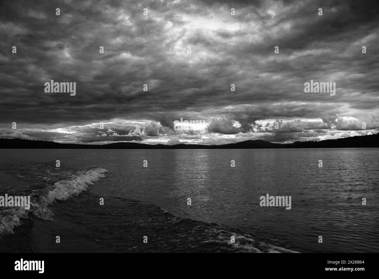 Boat wake on lake with dramatic clouds Stock Photo