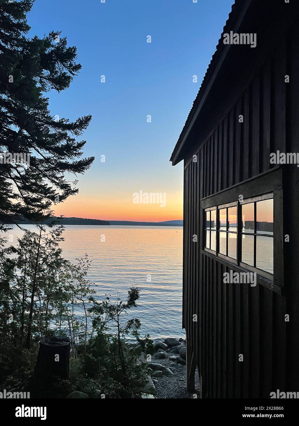 Lake sunset with boathouse window reflection Stock Photo