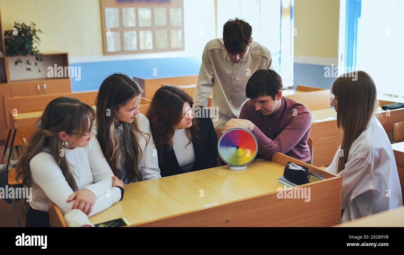 Students in physics class spin Newton's multicolored disk. Stock Photo