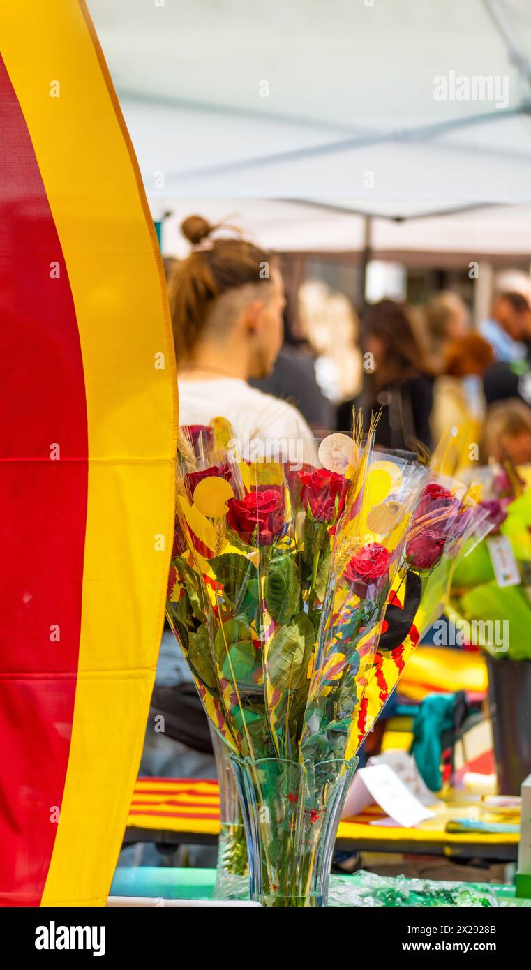 Bouquet of roses decorated with ears of wheat and bows of the flag of Catalonia, at a flower and book stall in a traditional holiday market with peopl Stock Photo