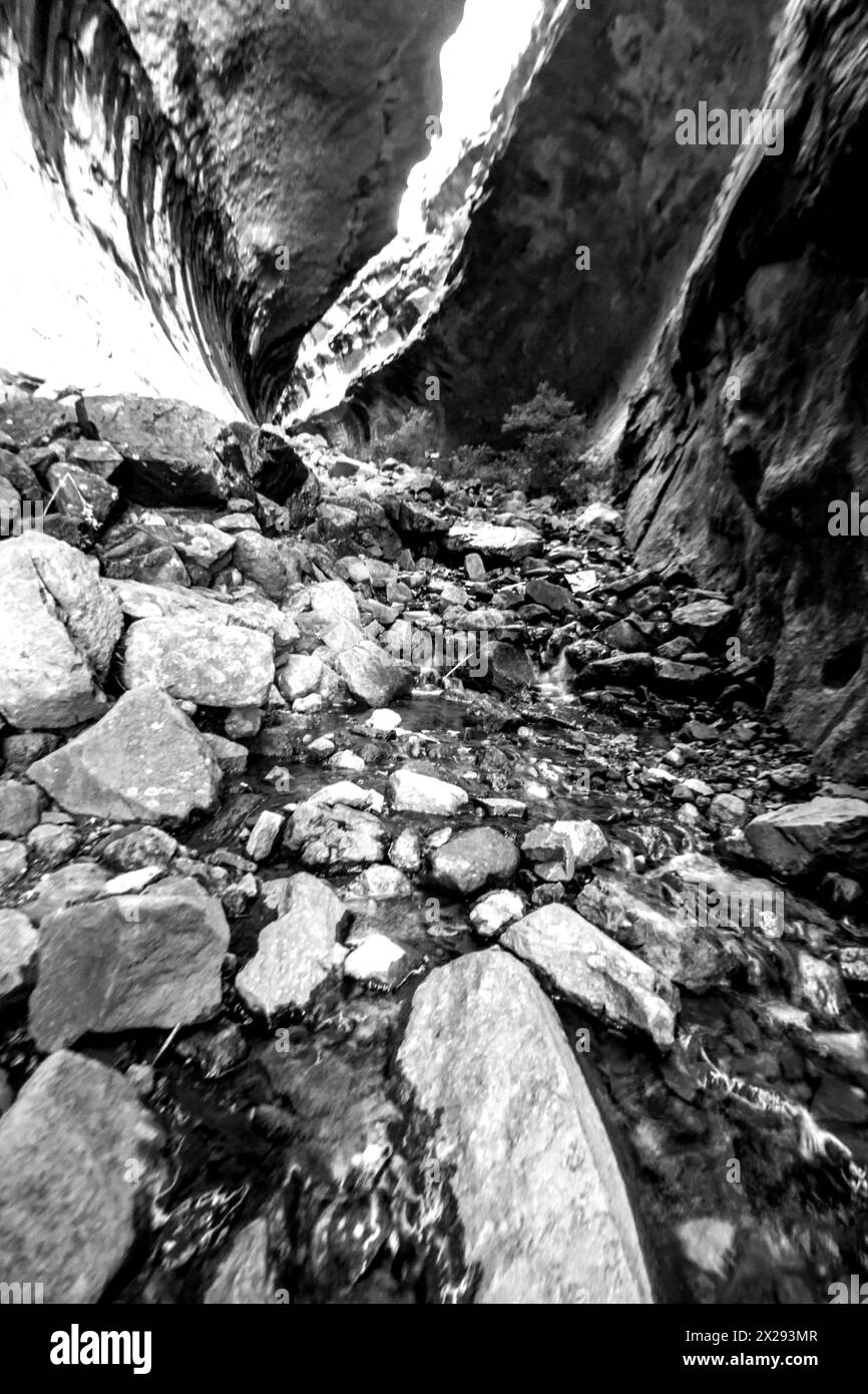 Black and white view of a stream flowing through a slot Canyon in the