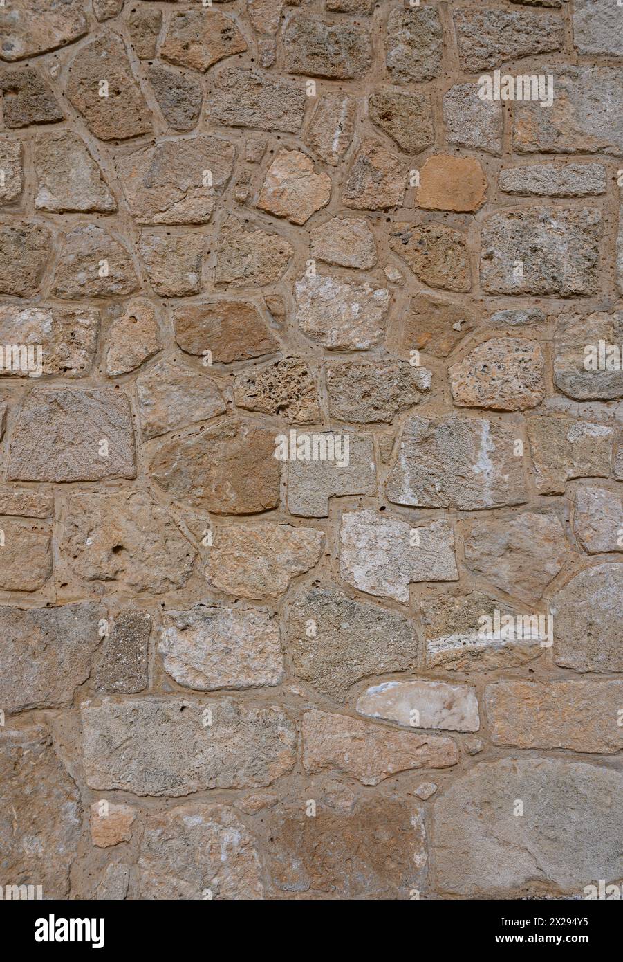 Light brown stone wall in panoramic close-up made of old, roughly hewn, different natural stones 1 Stock Photo
