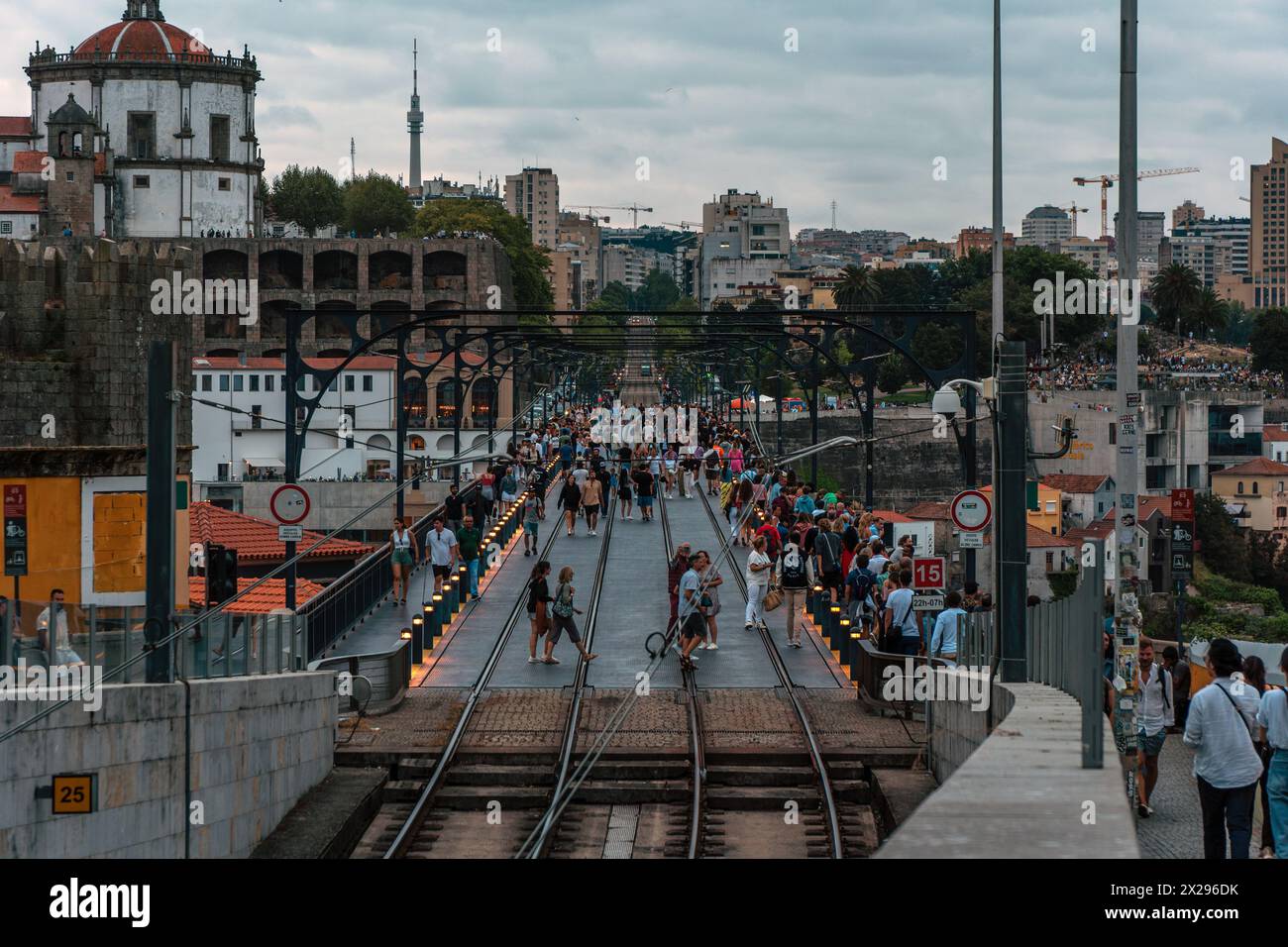 Panoramic view of the Porto Metro train track from the Dom Luis Bridge at dusk, with the lights on the poles full of tourists walking under a cloudy s Stock Photo