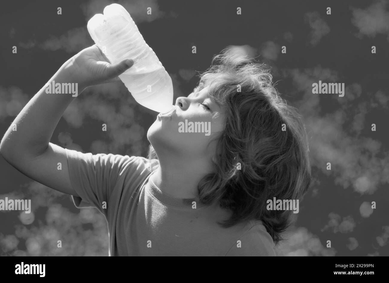 Child drinking water. Kid enjoy pure fresh mineral water. Outdoor kid boy drinking pure bottle from glass. Close up portrait of kid drinking water in Stock Photo