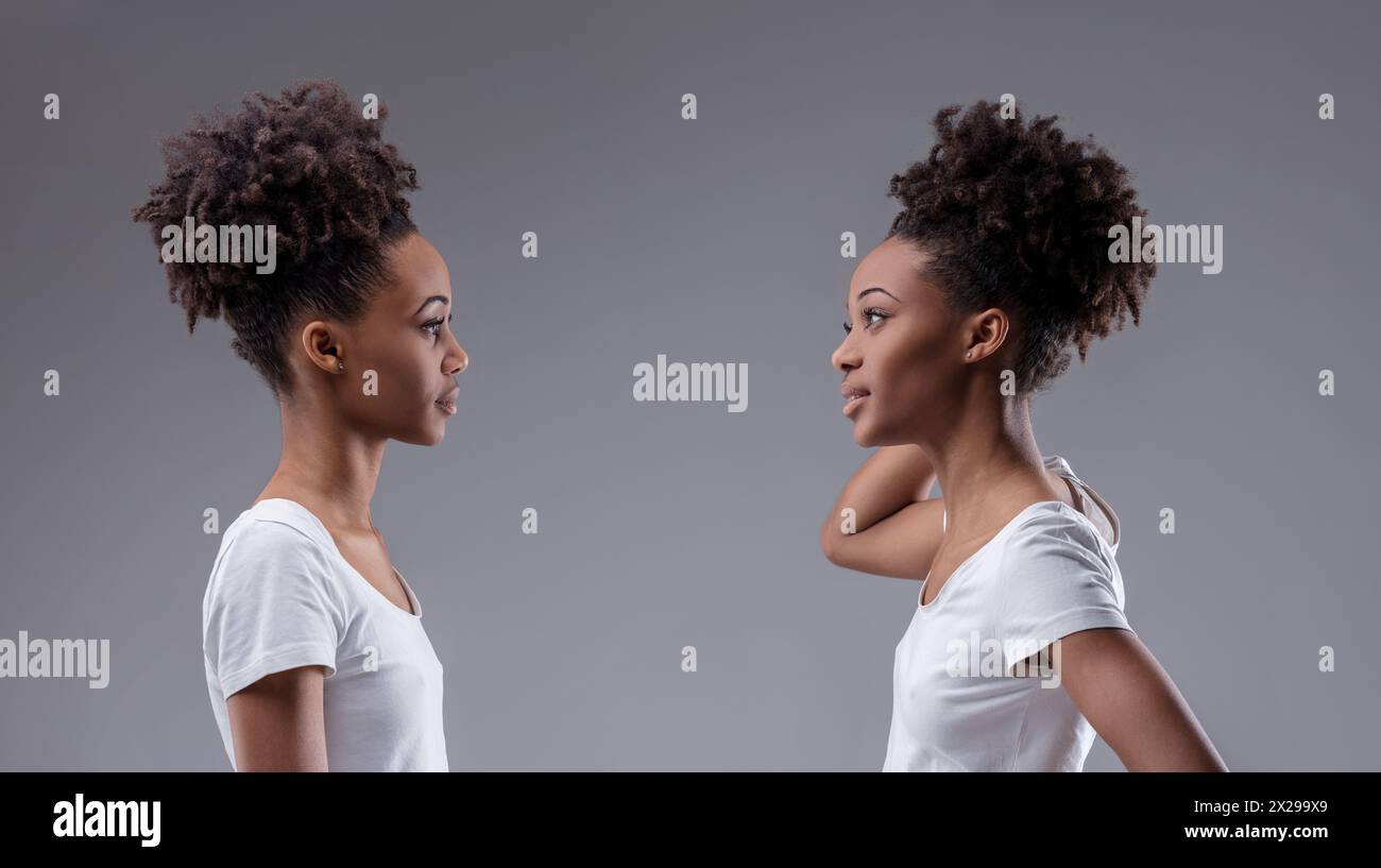 Self-doubt and scrutiny interplay in the stance of a young black woman evaluating her reflection Stock Photo