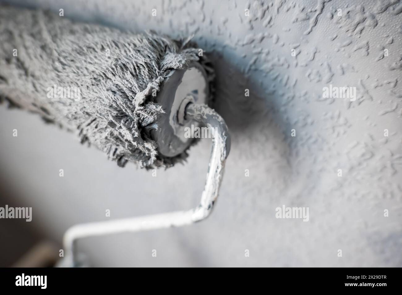 Paint roller extendable pole over painted woodchip wallpaper wall