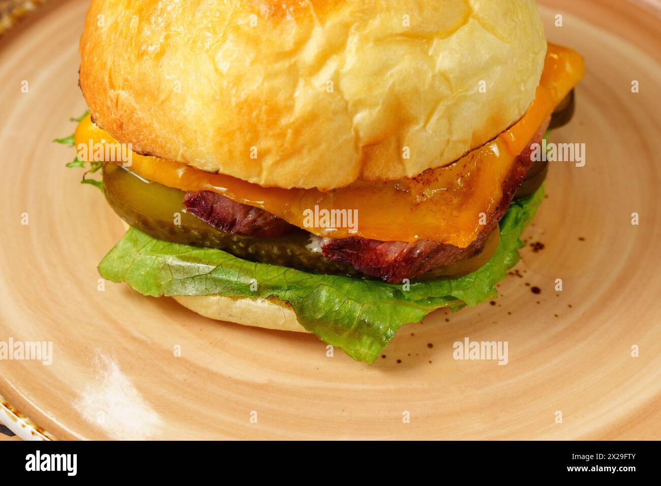 Cheeseburger is beef patty, melted cheese, fresh lettuce, and ripe tomato are clearly visible. Stock Photo