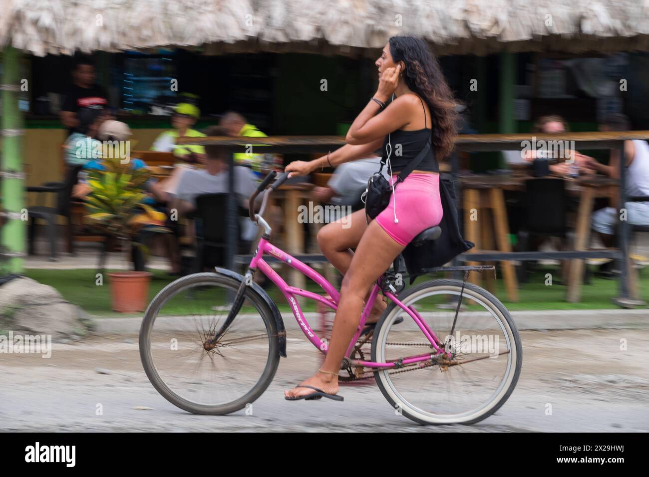Young woman riding a bicycle through the streets of Puerto Viejo de Talamanca in Costa Rica Stock Photo
