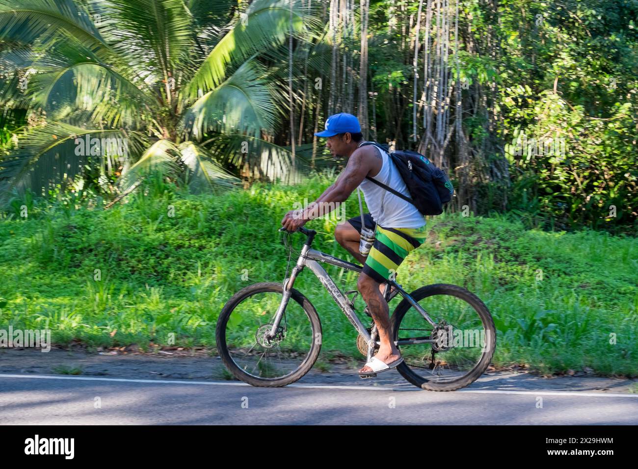 Man riding a bicycle on the road in Puerto Viejo de Talamanca in Costa Rica Stock Photo
