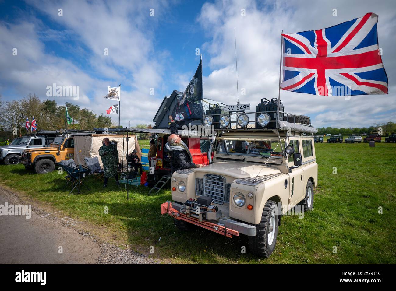 A man errects flags on his classic Landy campsite during the Great