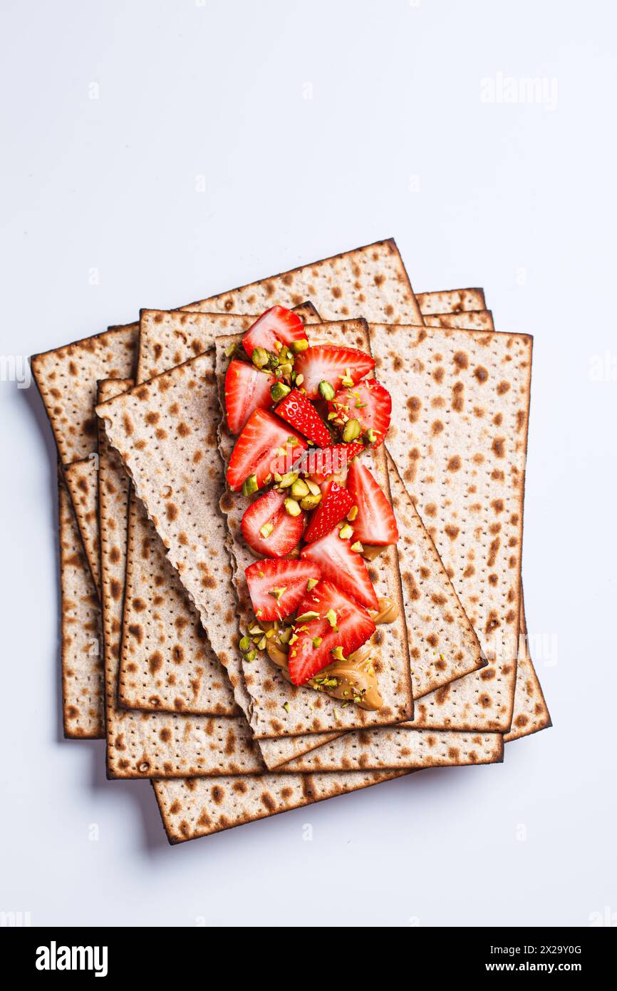 Matzah toast with peanut butter, strawberries and pistachios on a white
