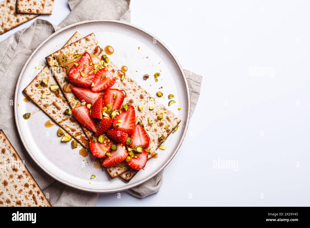 Matzo toast with peanut butter, strawberries and pistachios on a white