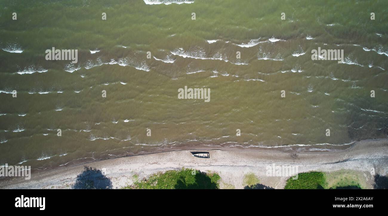 Small boat in lake shore aerial drone top view on bright sunny day Stock Photo