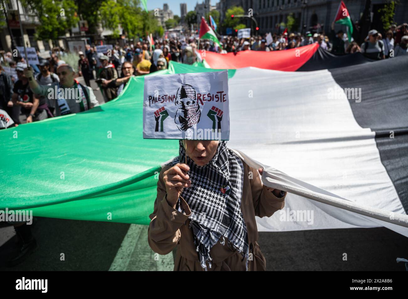 Madrid, Spain. 21st Apr, 2024. People carrying a large Palestinian flag during a demonstration in support of the Palestinian people. Thousands of people rally in Madrid under the slogan 'stop genocide in Palestine' demanding the end of arms trade with Israel and a definitive ceasefire in the Gaza Strip. Credit: Marcos del Mazo/Alamy Live News Stock Photo