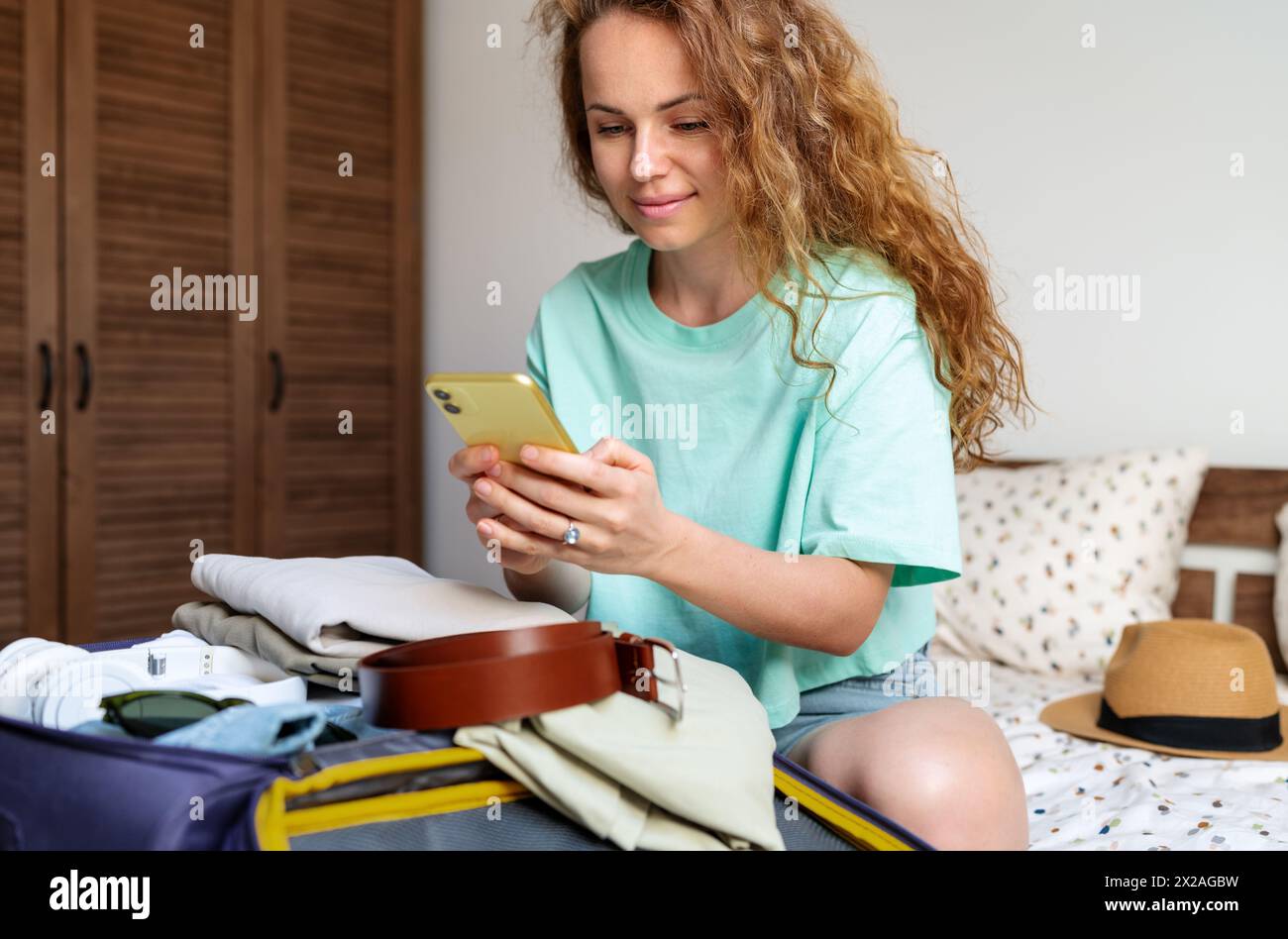 Online booking a hotel and buying flight e-tickets using smartphone. Woman prepares for traveling. Stock Photo