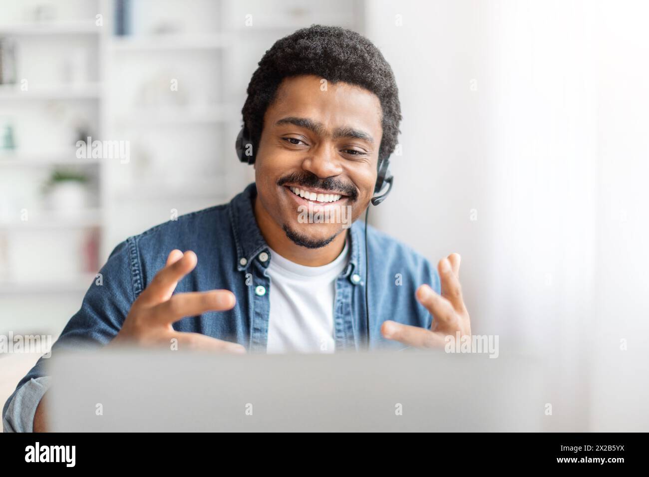 Smiling black man with headset using laptop Stock Photo