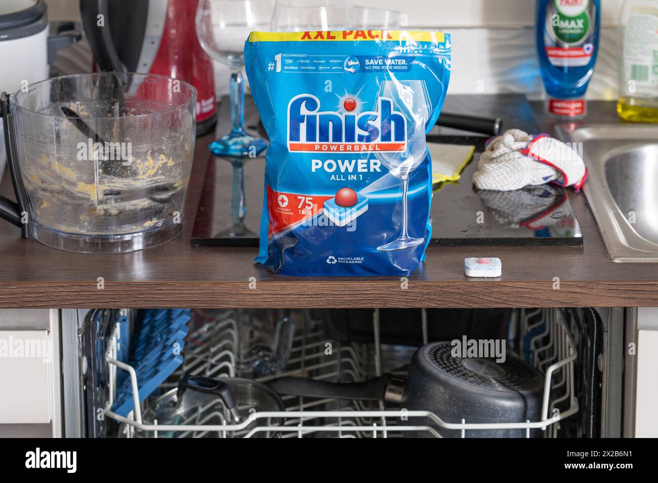 Finish Powerball Power All in 1 pack of dishwasher tablets on a kitchen surface with dirty washing up around and a dishwasher below. England Stock Photo