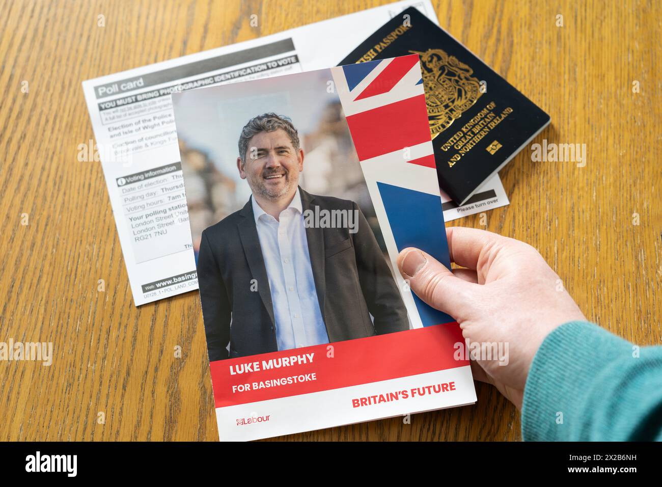 Man's hands holding a Luke Murphy Labour flier for local Basingstoke elections in May 2024, with a poll card and a passport behind. England Stock Photo