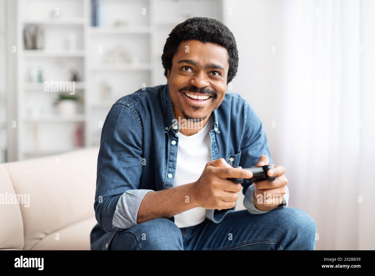 Man with a game controller grinning widely Stock Photo