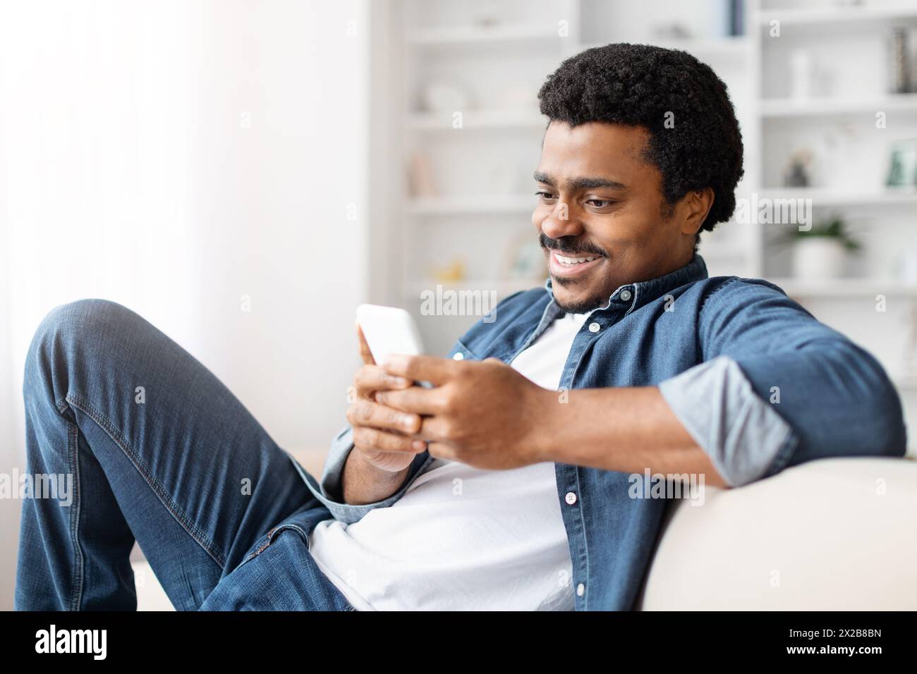 Happy black man using smartphone at home Stock Photo