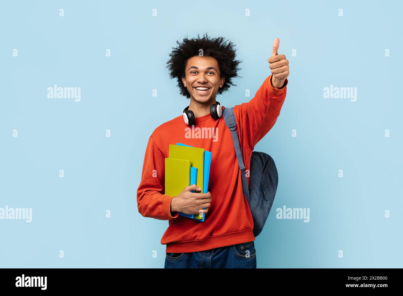 Positive student with books showing thumbs up Stock Photo - Alamy