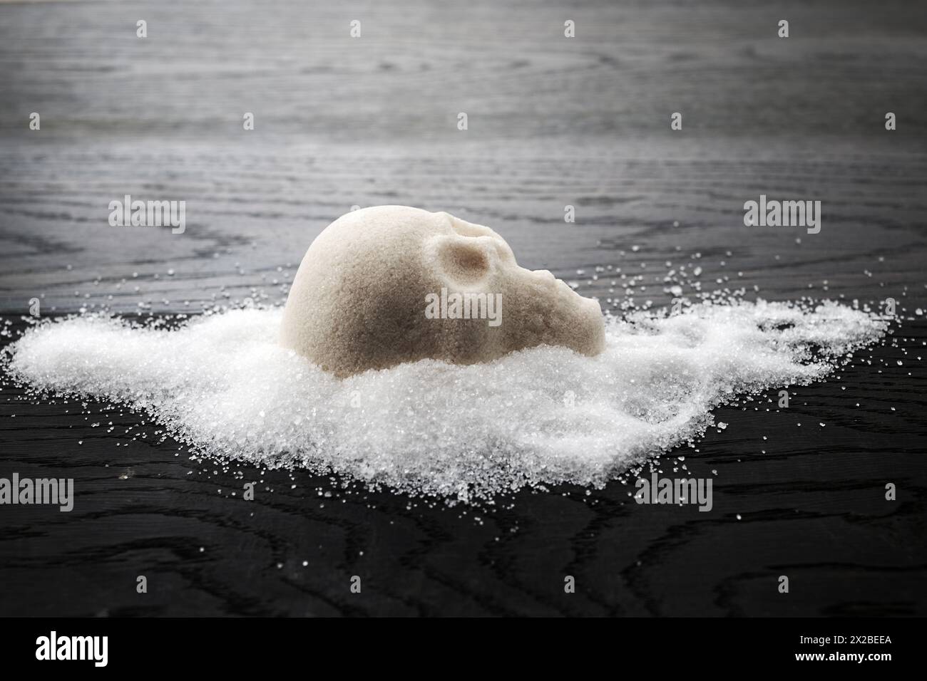A skull-shaped sugar mound on a wooden surface symbolizing the concept of unhealthy diet Stock Photo