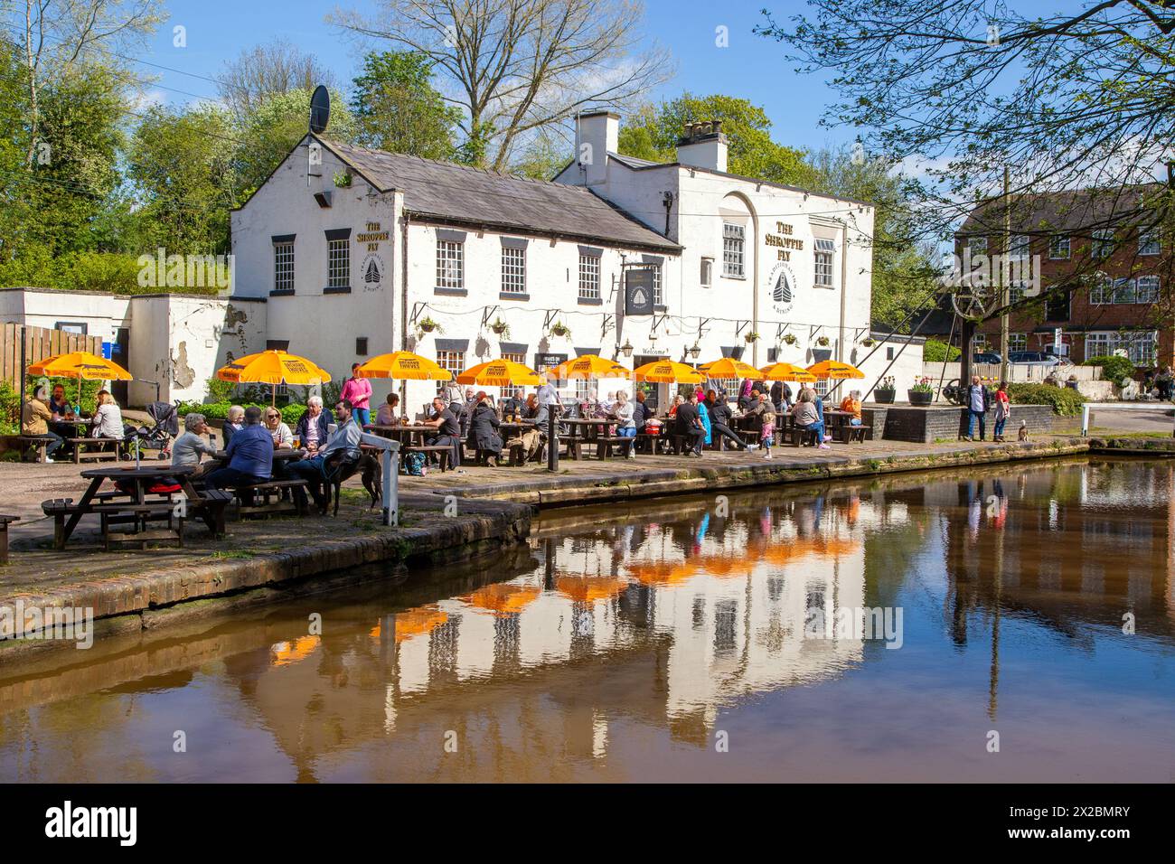 People sitting outside eating and drinking at the canalside pub the Shroppie fly in the Cheshire village of Audlem Cheshire England Stock Photo