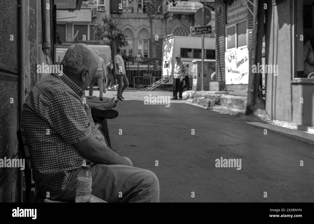 04.18.2024,Basmane,Izmir,Turkey,An old man sitting on the streetside watching people pass by Stock Photo