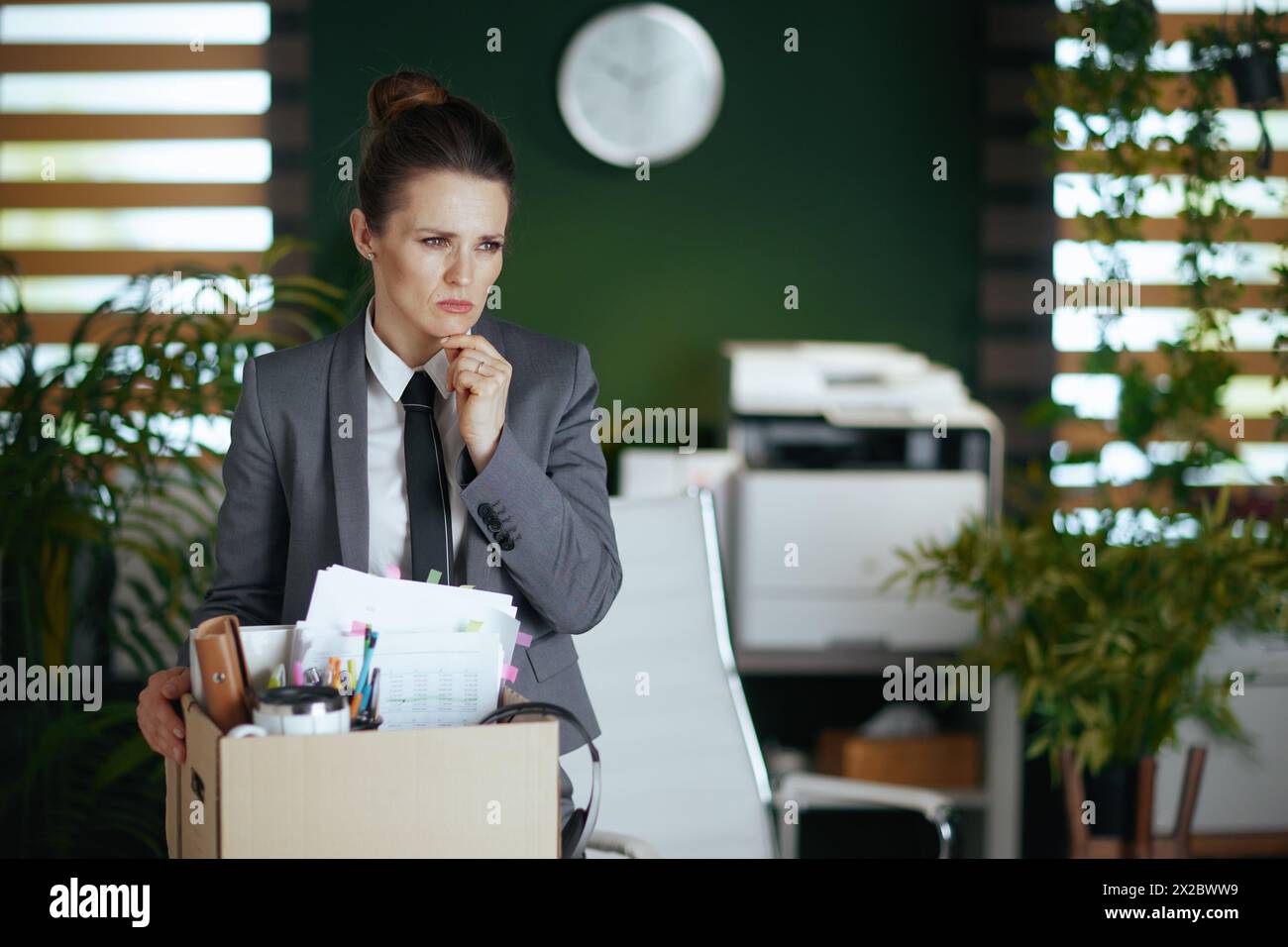 New job. pensive modern female worker in modern green office in grey ...