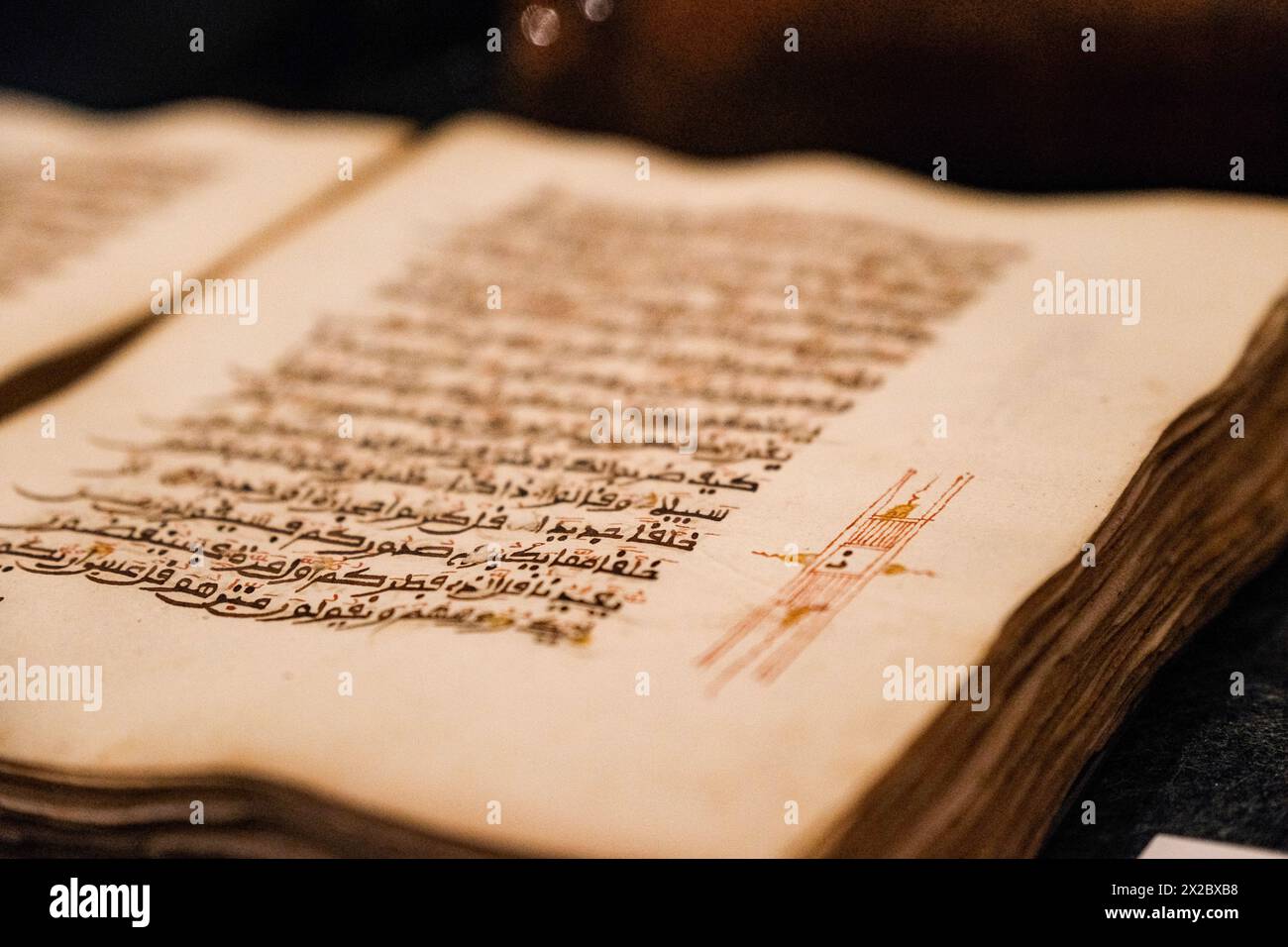 An enchanting bokeh capturing the allure of red decorations on an open page of a historic Quran. Stock Photo