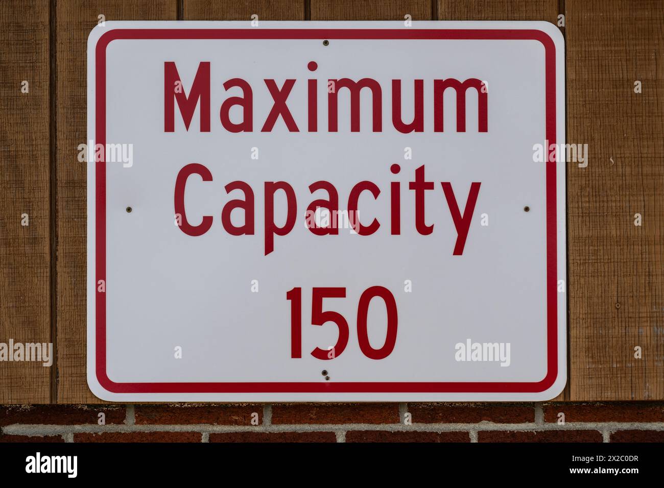 Red and white metal sign indicating maximum capacity at the beach house in Speculator, NY on Lake Pleasant Stock Photo