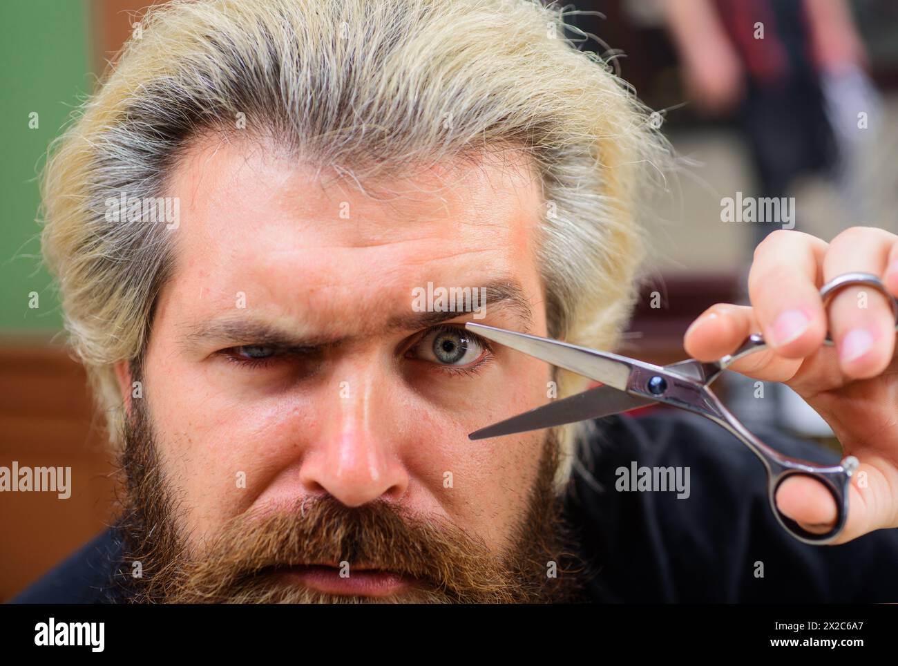 Barbershop concept. Closeup portrait of stylish bearded man with barber scissors. Men's haircut in barber shop. Hairdresser scissor. Professional Stock Photo