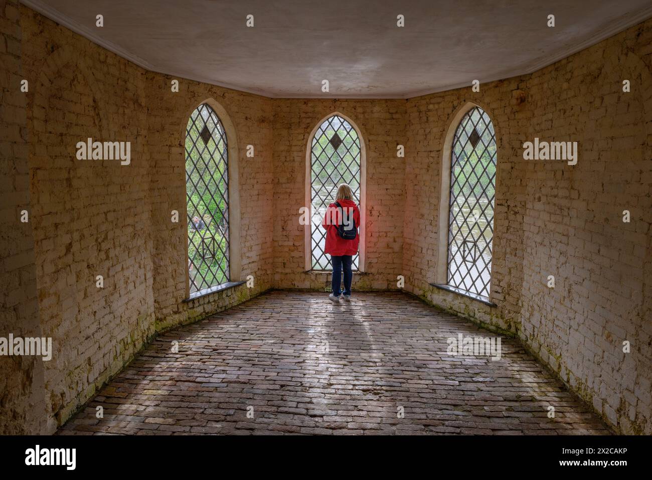 Woman inside the Museum of The Gorge looking out through metalled lattice windows, Ironbridge, Shropshire, UK Stock Photo