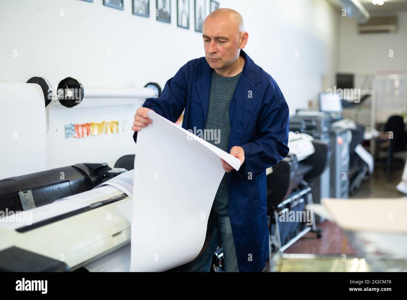Service man uses plotter and checks functionality in printing shop Stock Photo